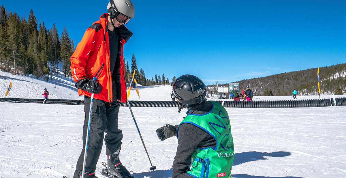 harrison being coached on how to ski on amputee ski trip