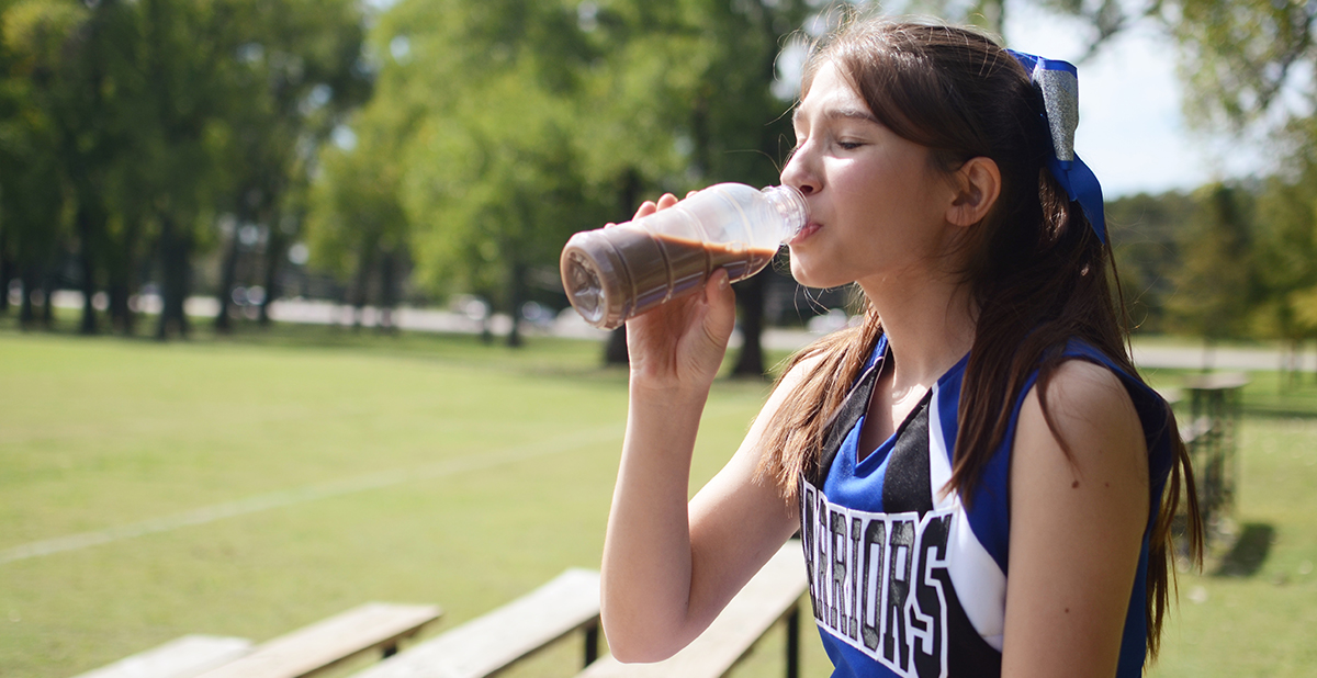 Young athlete drinking chocolate milk after a practice. 