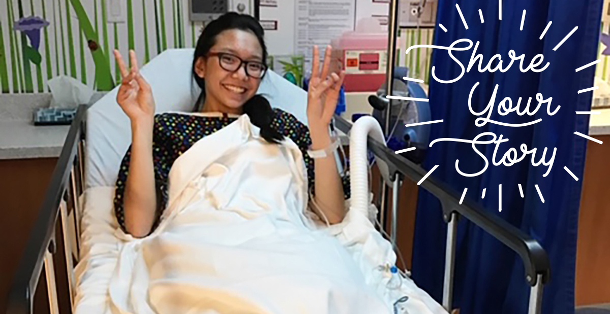 girl in hospital bed smiling and giving peace sing 