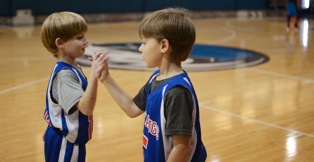 Children on basketball court give each other high fives