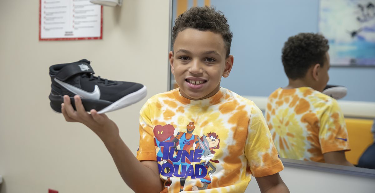 Patient, Caden, holding Nike shoes with Zippers