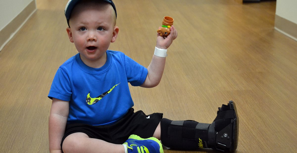 Toddler with a broken foot plays with toys