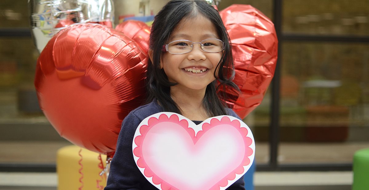 Texas Scottish Rite Hospital for Children patient surrounded by heart balloons