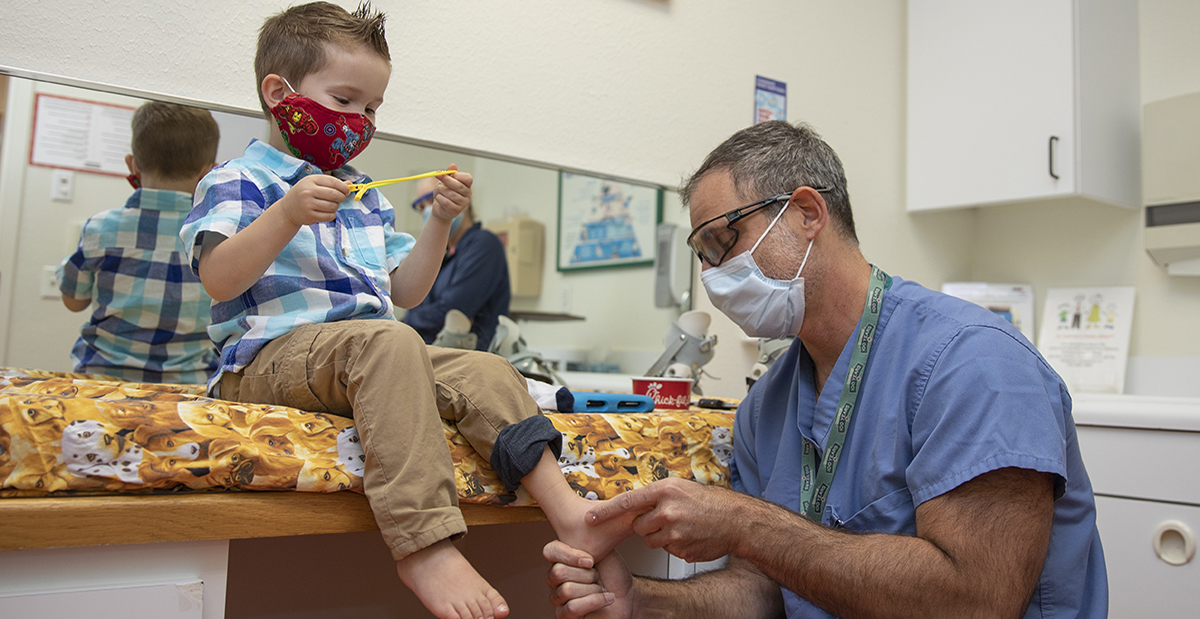 A boy wearing a red mask is being examined by a doctor