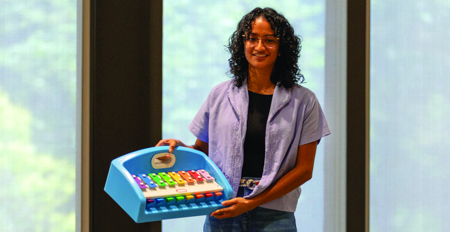 A woman in a purple shirt is holding a toy xylophone