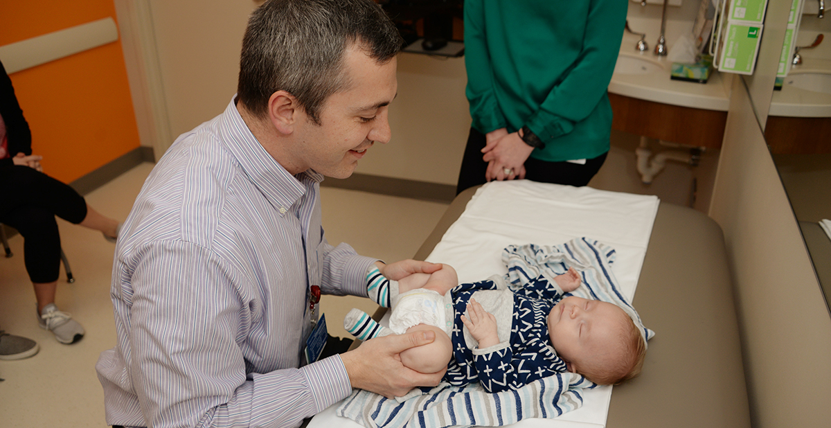 Dr. Gill examining a baby's hips in clinic.