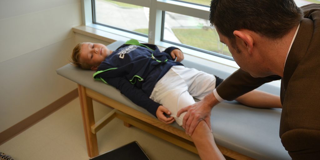 Dr. Ellis evaluating a patient's knee in clinic.