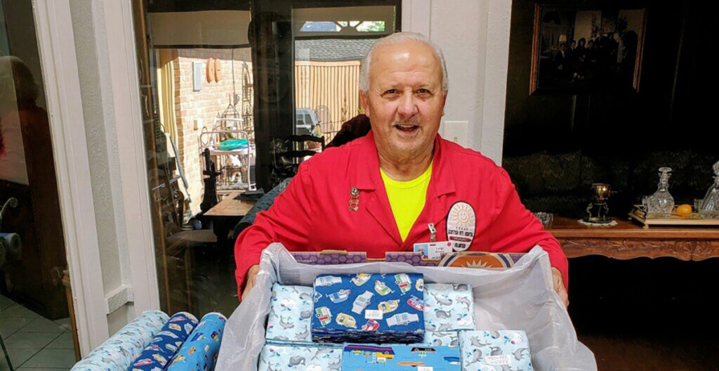 A man in a red jacket holds a box of wrapping paper