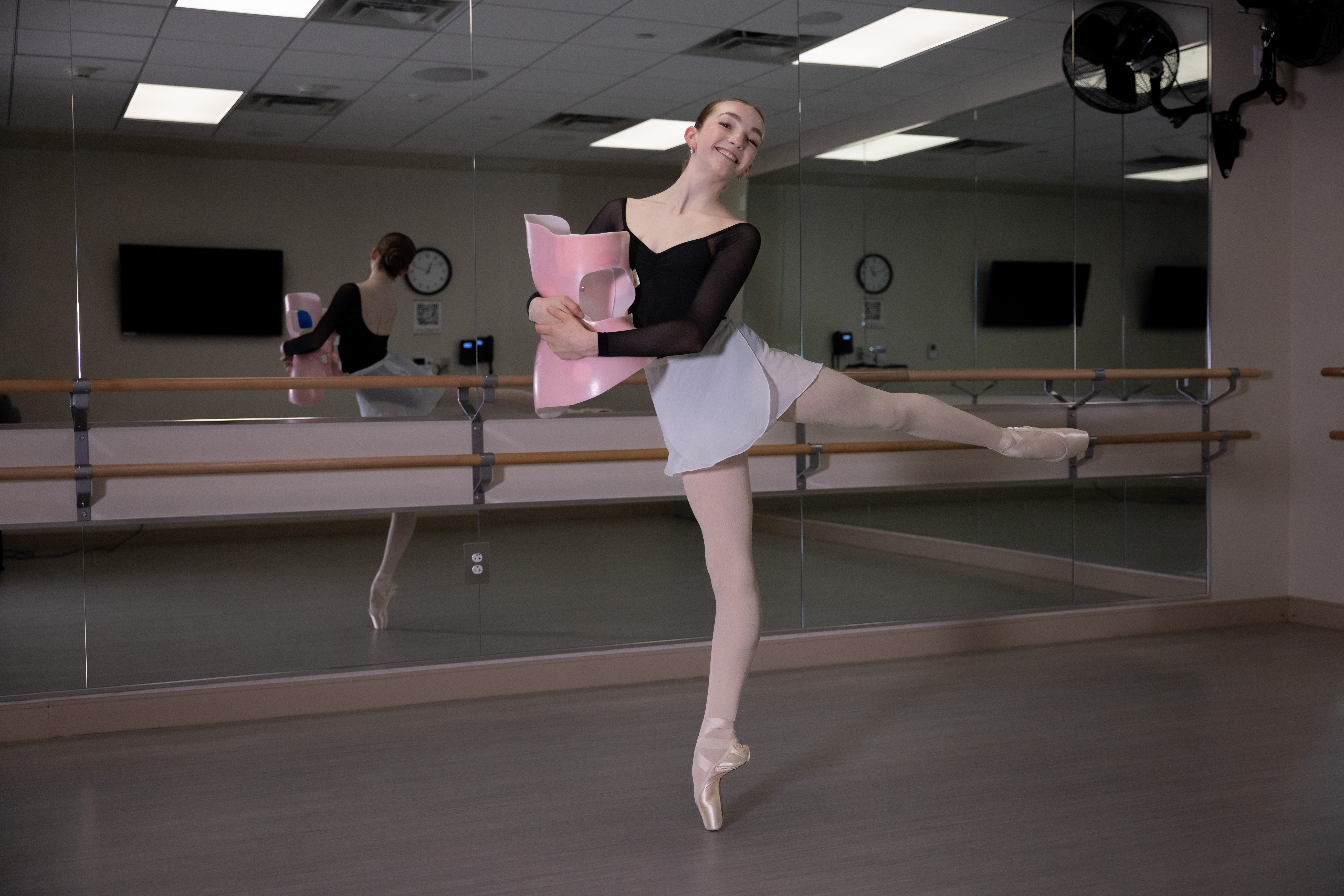 Avery Stafford dancing ballet and holding her scoliosis brace.