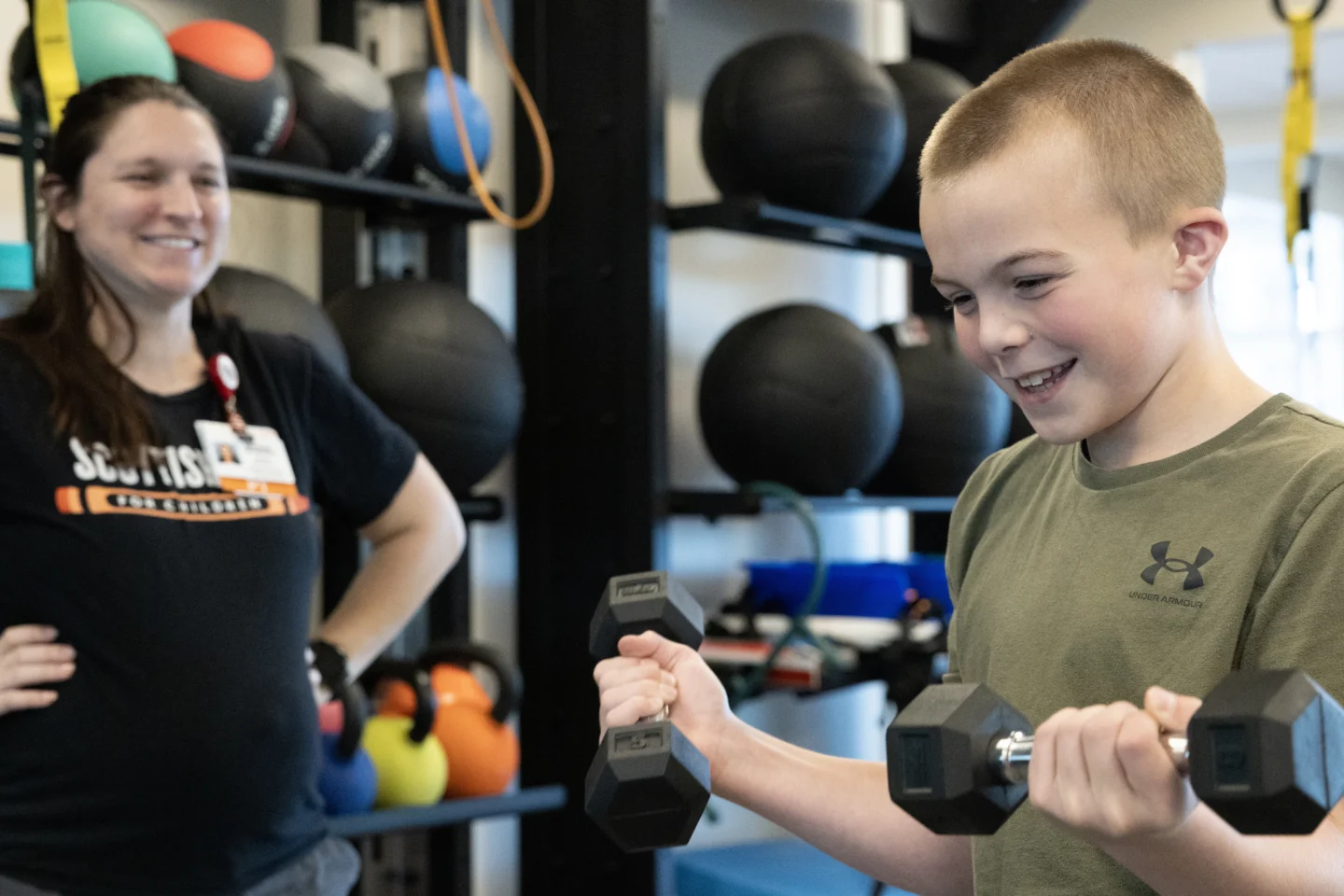 Young boy lifting weights with a physical therapist.