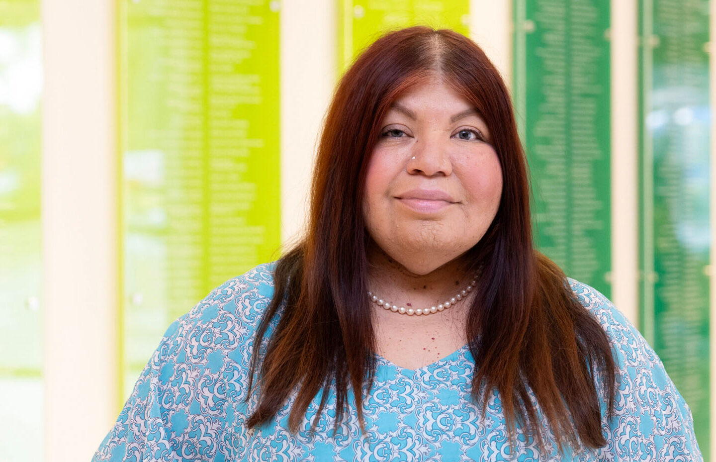 Staff member Gloria standing in front of a colorful wall.