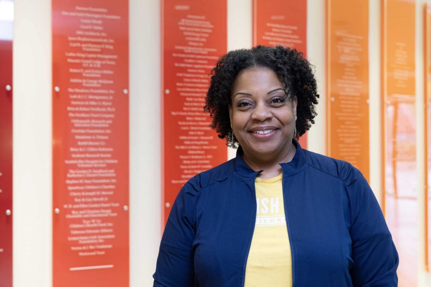 Staff member Michelle standing in front of colorful wall.