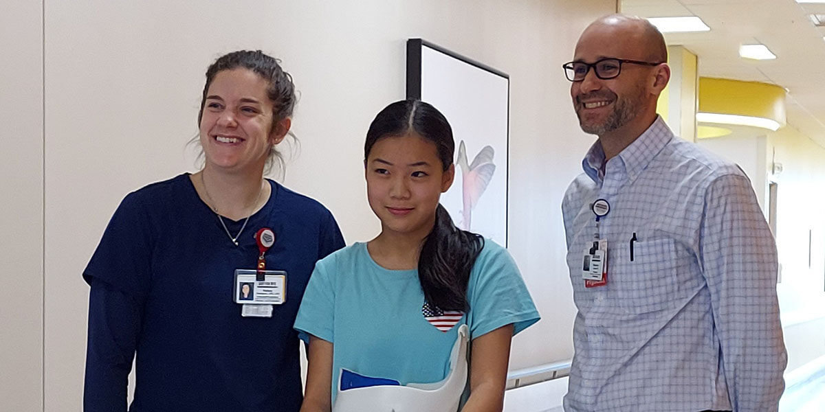 Danielle standing with SRC doctor and nurse with her scoliosis brace.