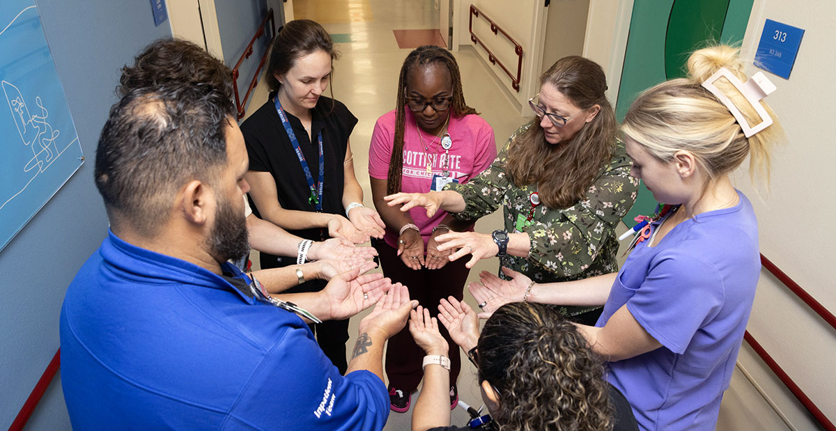 Jerilynn Putnam prays with Scottish Rite for Children's staff members.